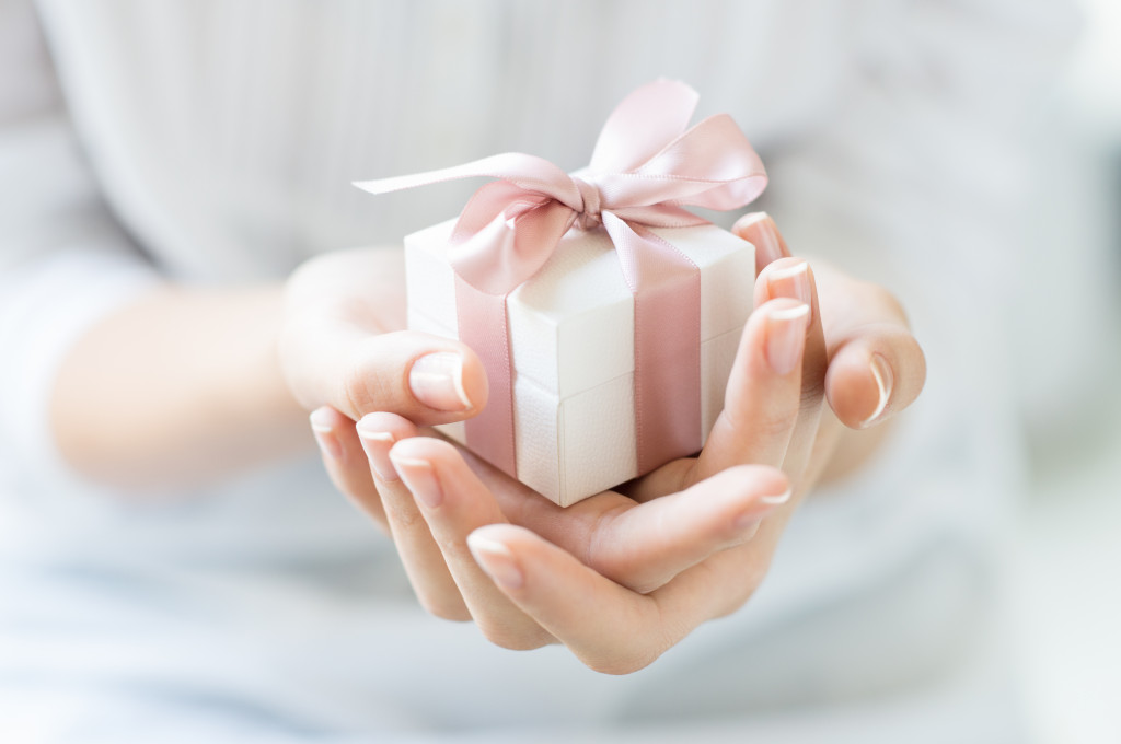 Close up shot of female hands holding a small gift wrapped with pink ribbon