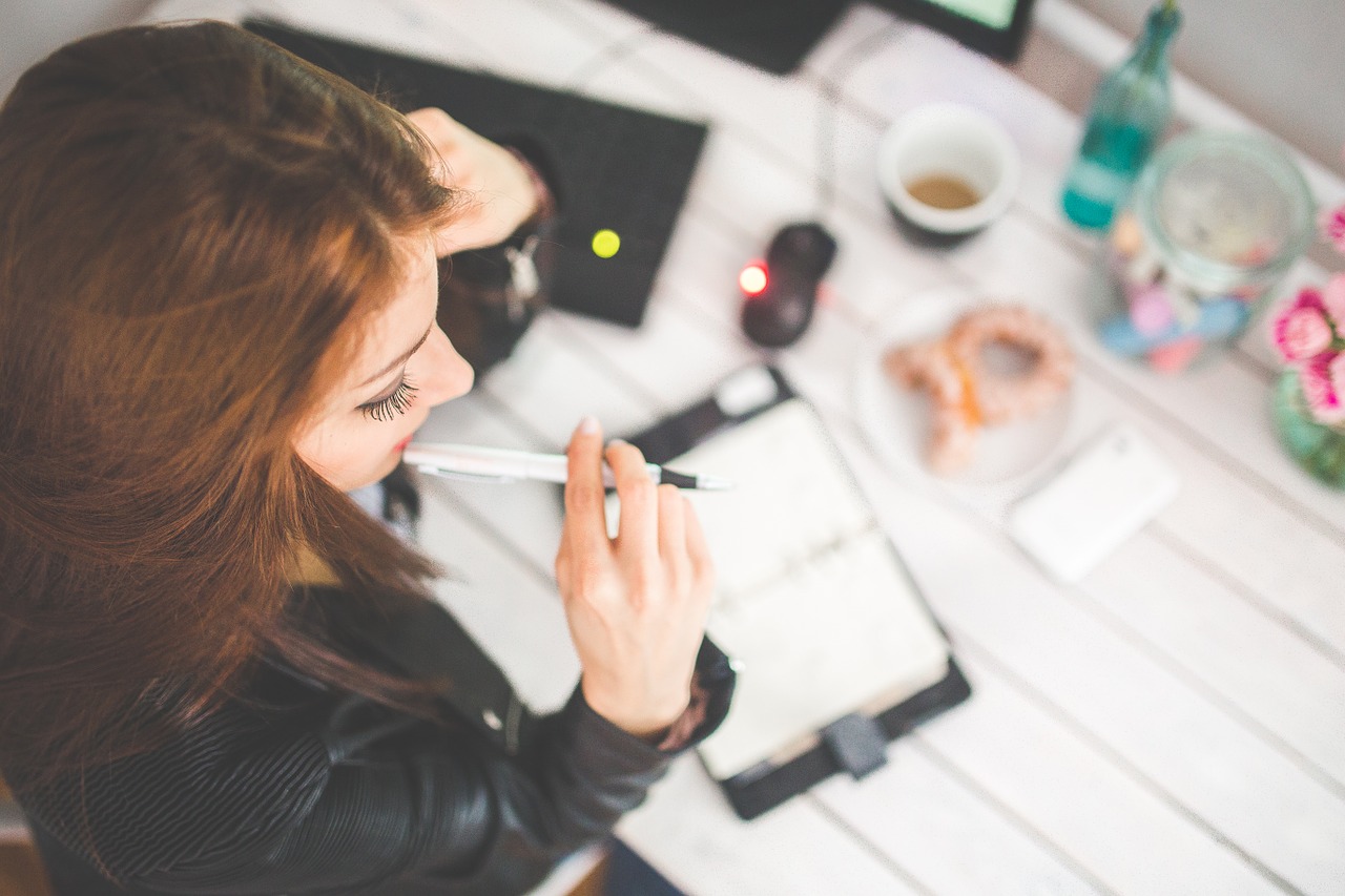 woman biting her pen while working