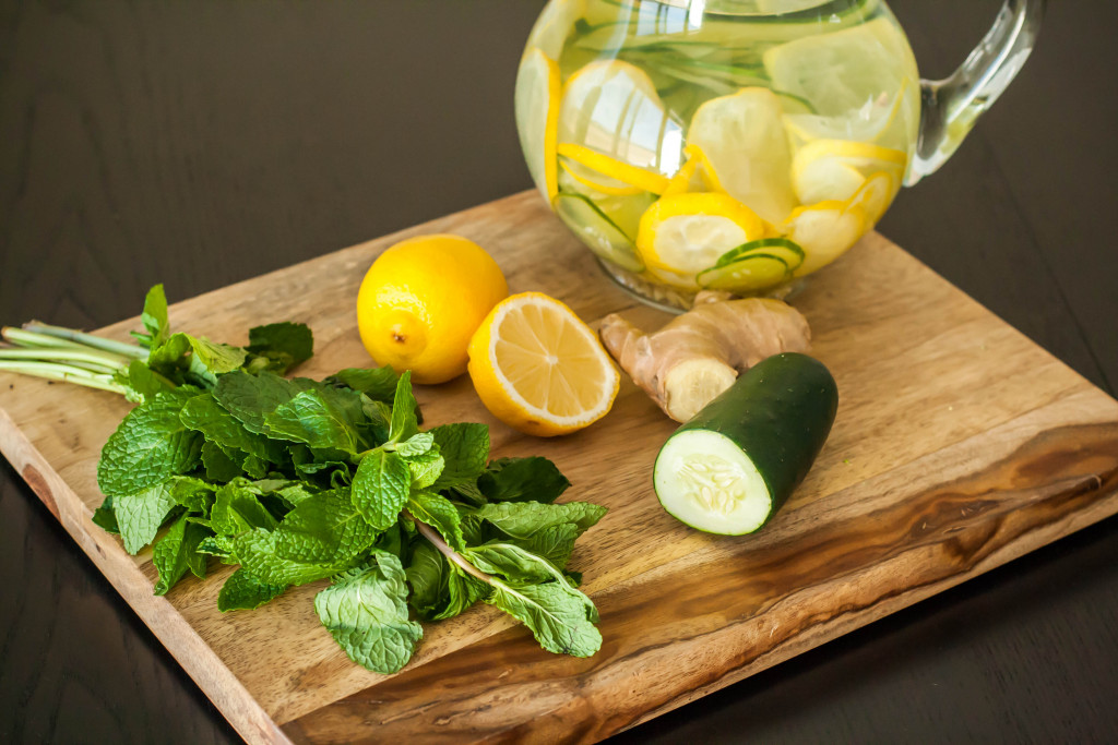 Fruits and vegetables on a chopping board with a pitcher of water filled with fruits.