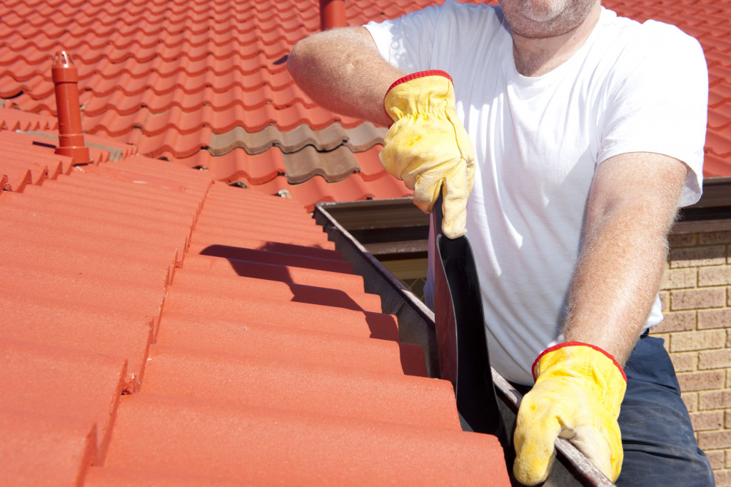 man cleaning house gutter