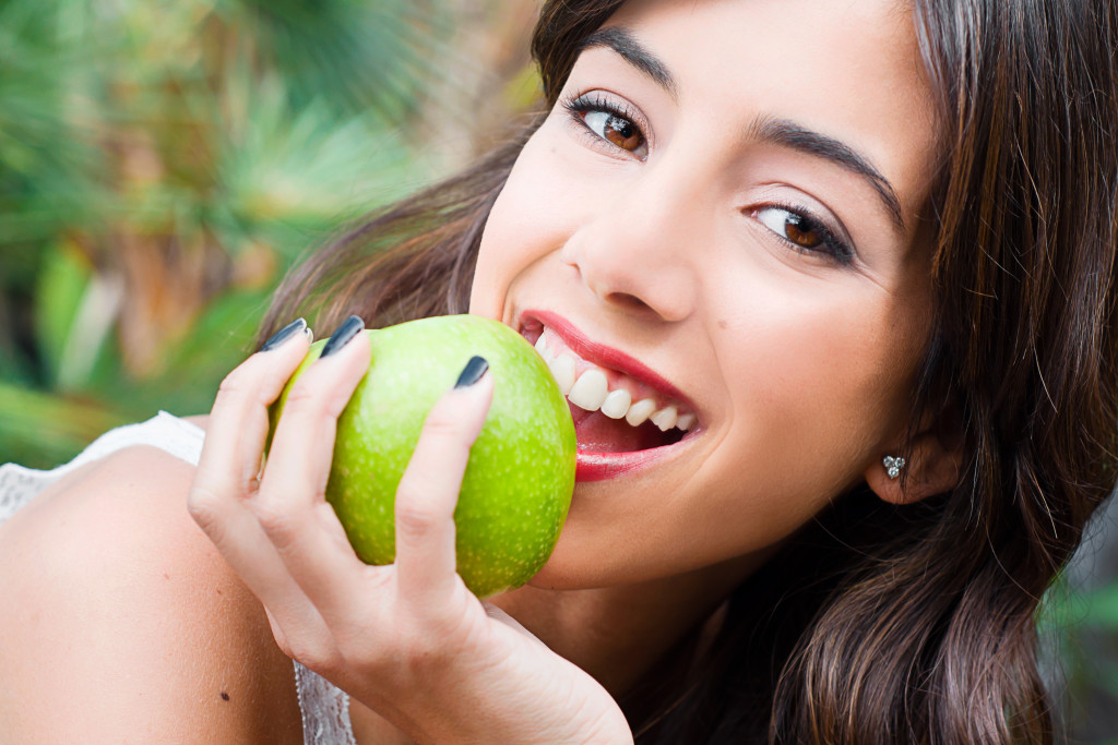 Young woman with beautiful skin eating fruit