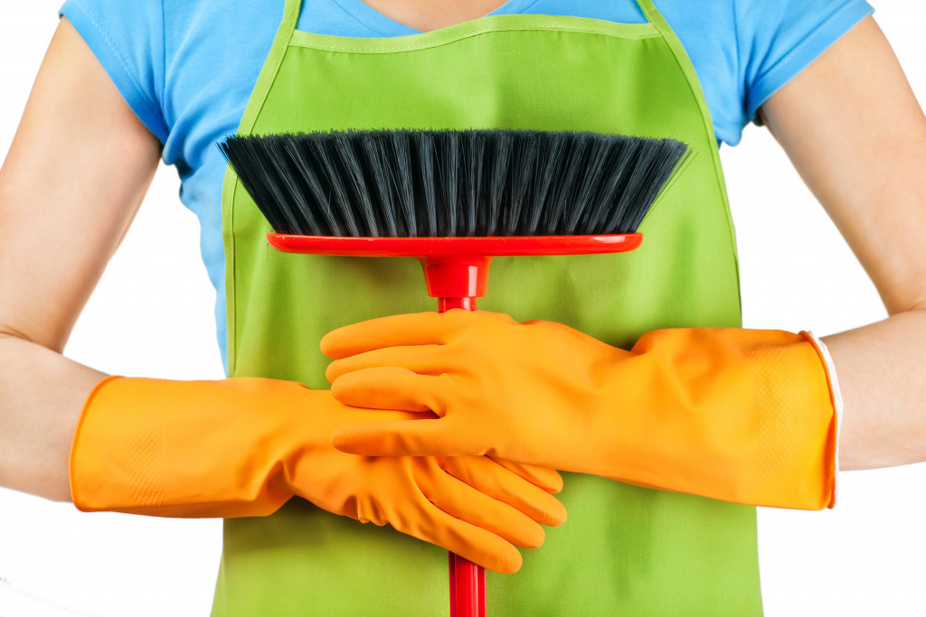 a woman holding a broom and wearing cleaning gloves