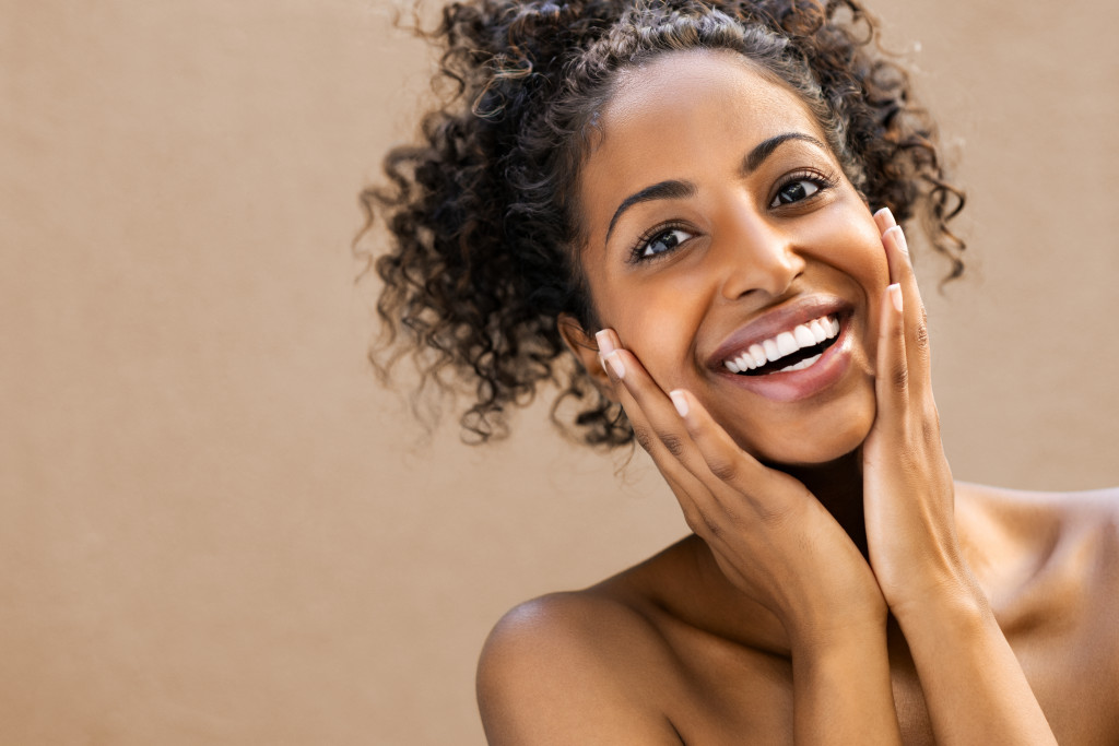 girl smiling while holding her face concept of skin care