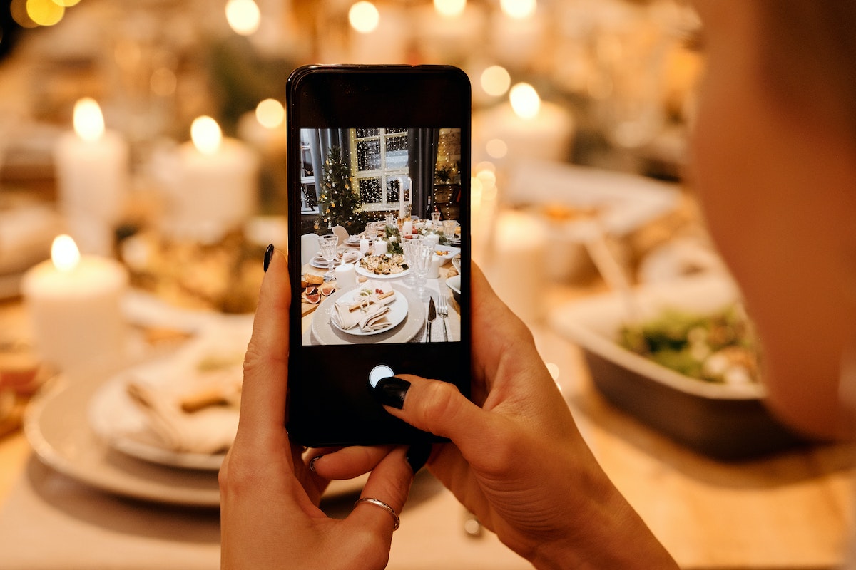 Woman Taking Photo of Food on Table