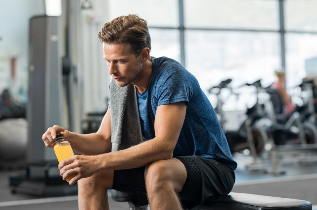 Young man taking a break after working out at a gym and drinking an energy drink.