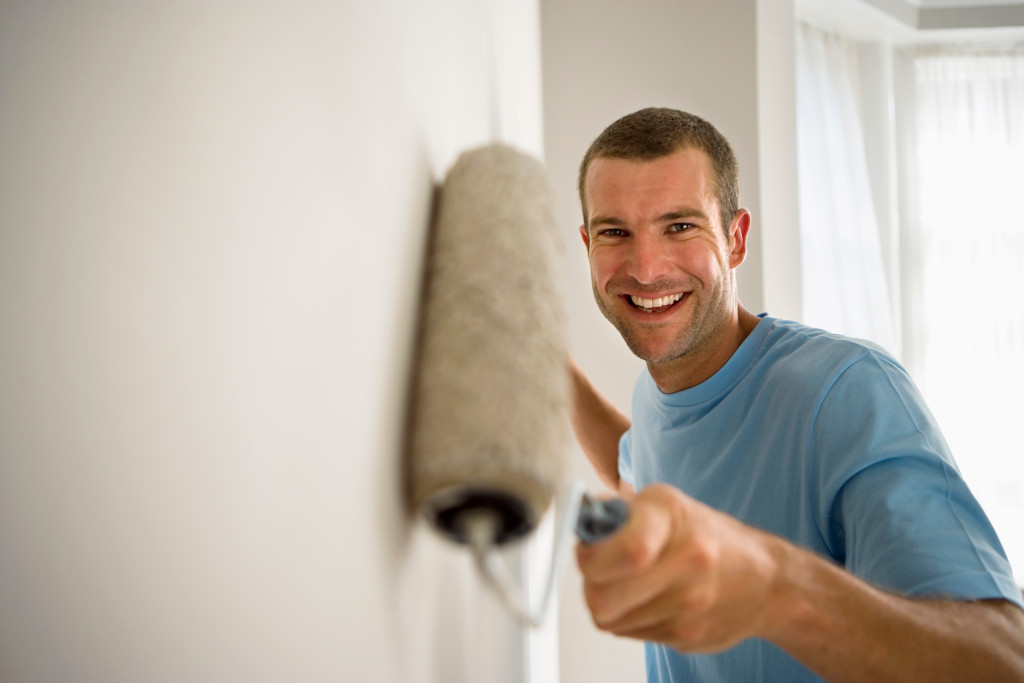 man painting the wall while smiling