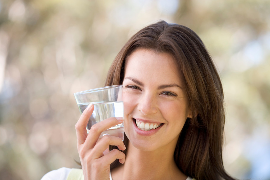 woman smiling while holding a glass of water