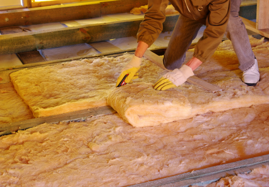 A construction worker installing insulation on house attic