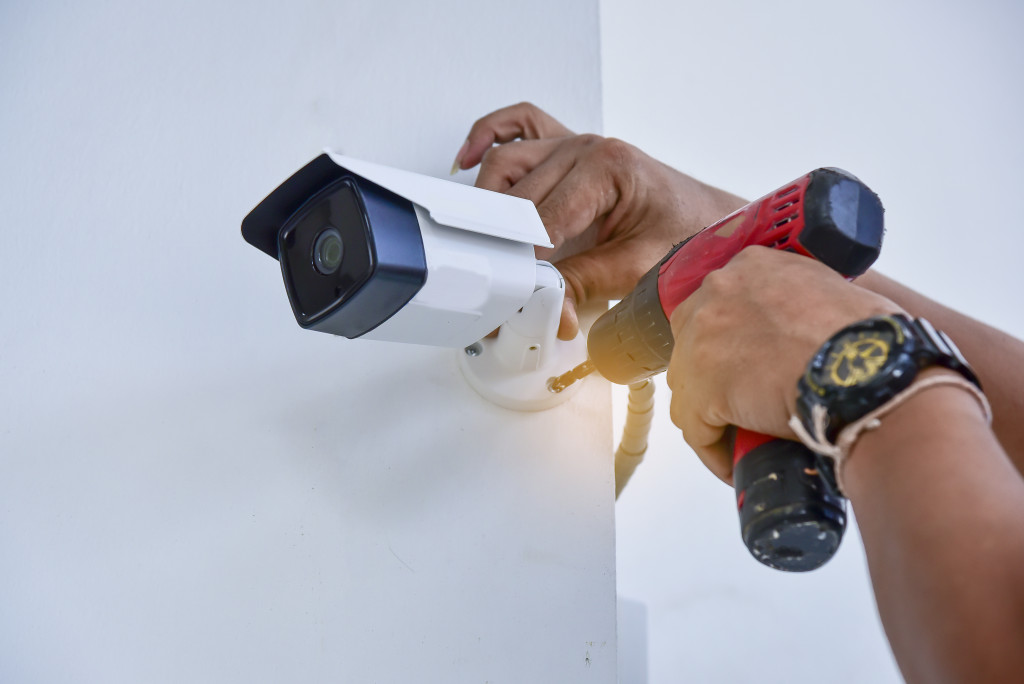 Technician installing a security camera on the wall at home.