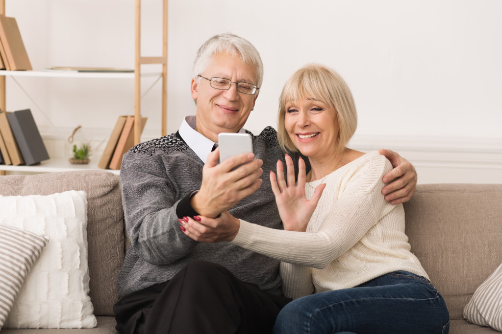 Senior couple talking with their family through a video call using a phone.