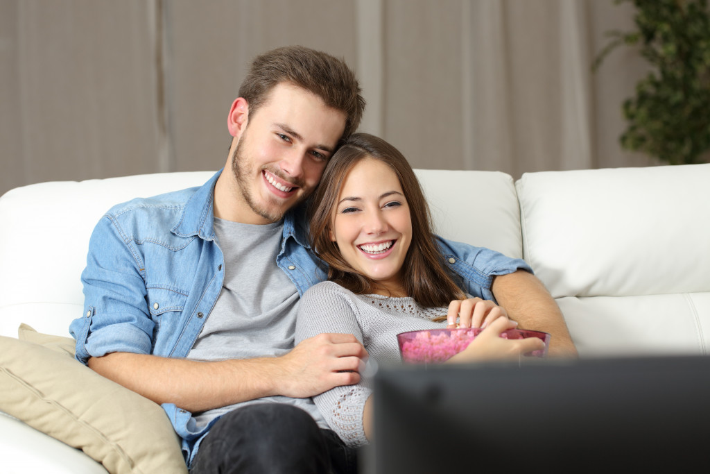 Young couple sitting on a couch with plush throws.